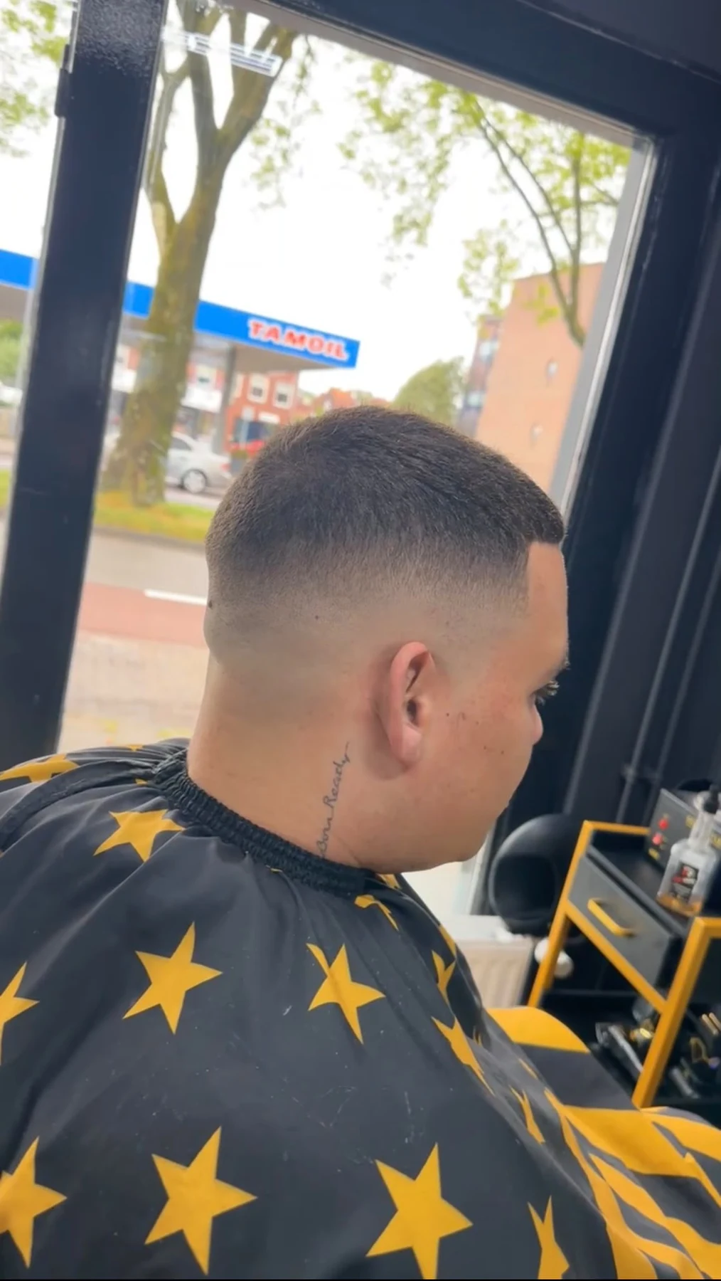 Strakke fade met goud-zwarte barbercape